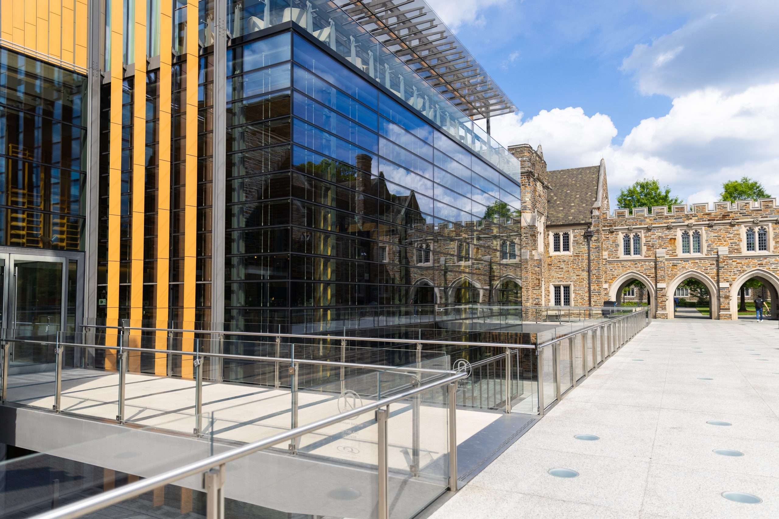 A glass building is featured adjacent to Duke University's gothic architecture.
