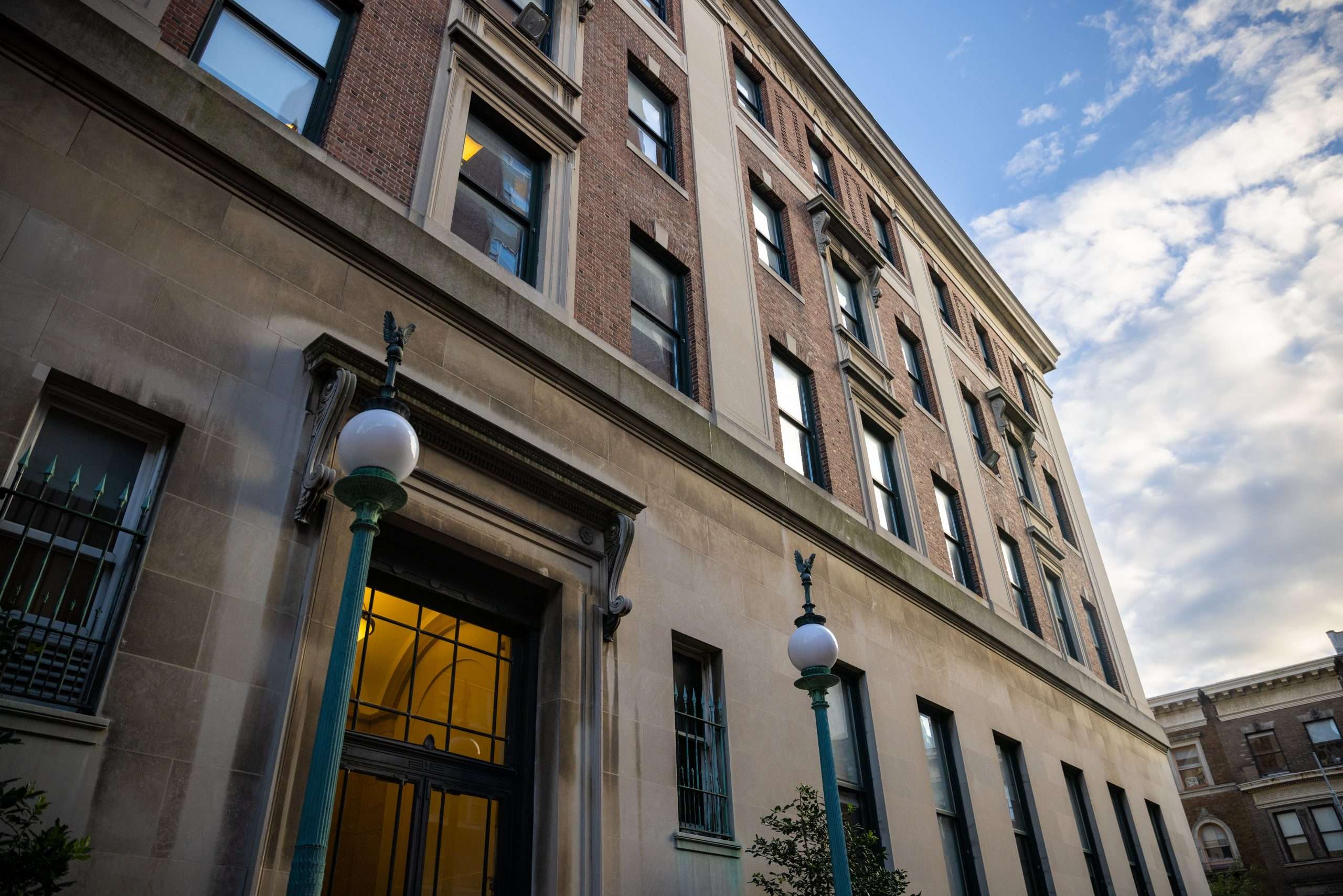 Two lamp posts stand on either side of a door leading into a brick Columbia University building.