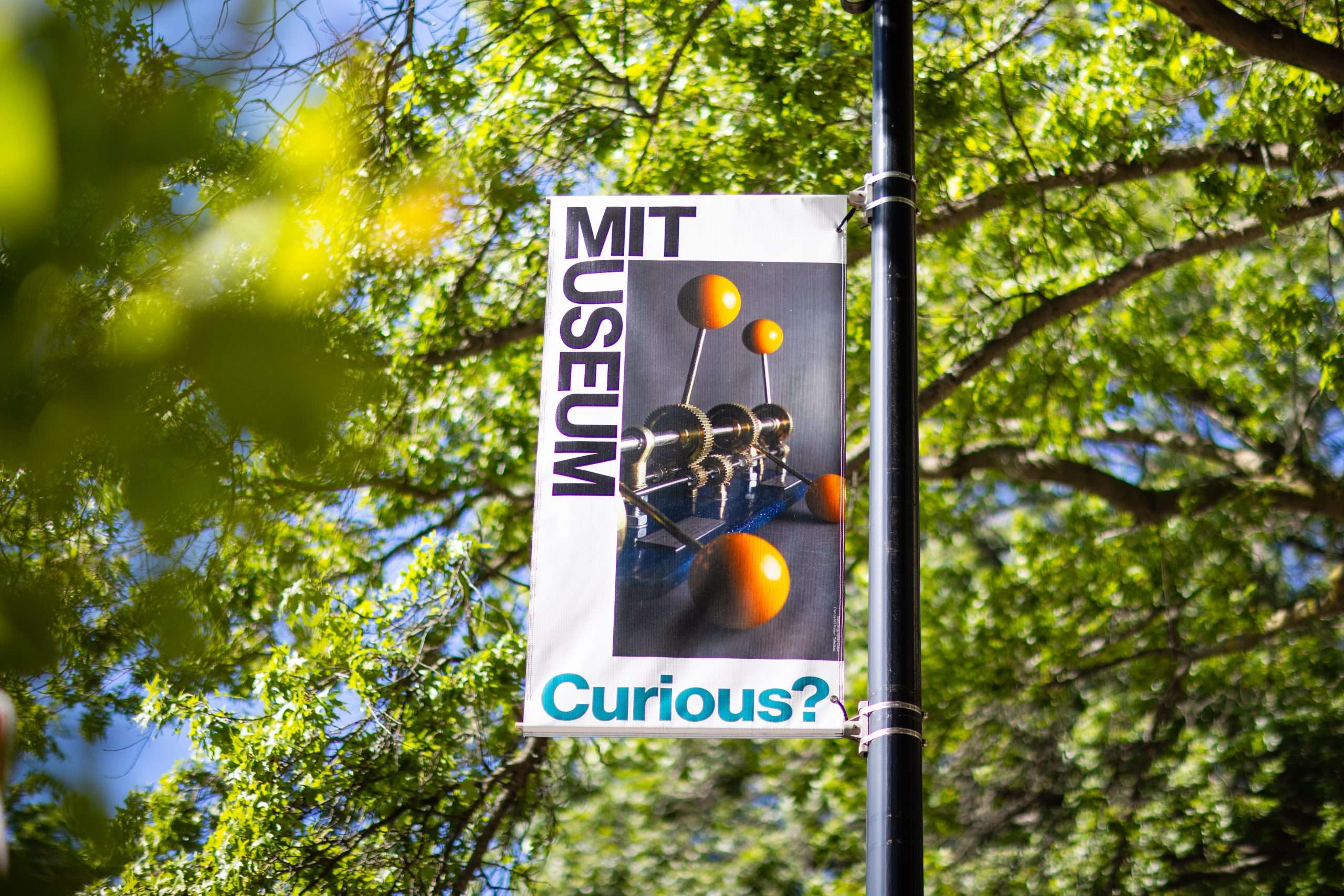 An MIT Museum banner hangs from a flagpole on MIT's campus.