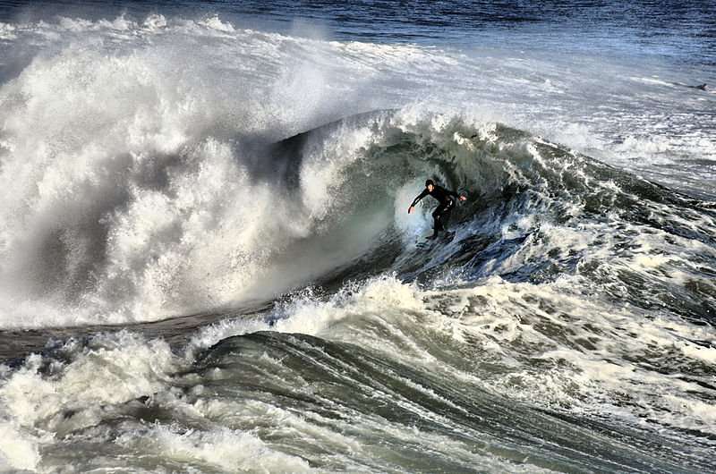 This is a portrait of a surfer riding a huge wave.