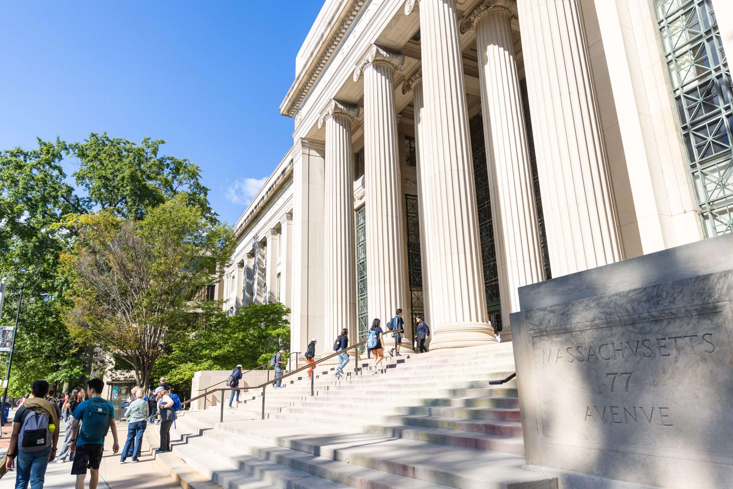 Students climb the steps of a columned building at the Massachusetts Institute of Technology.