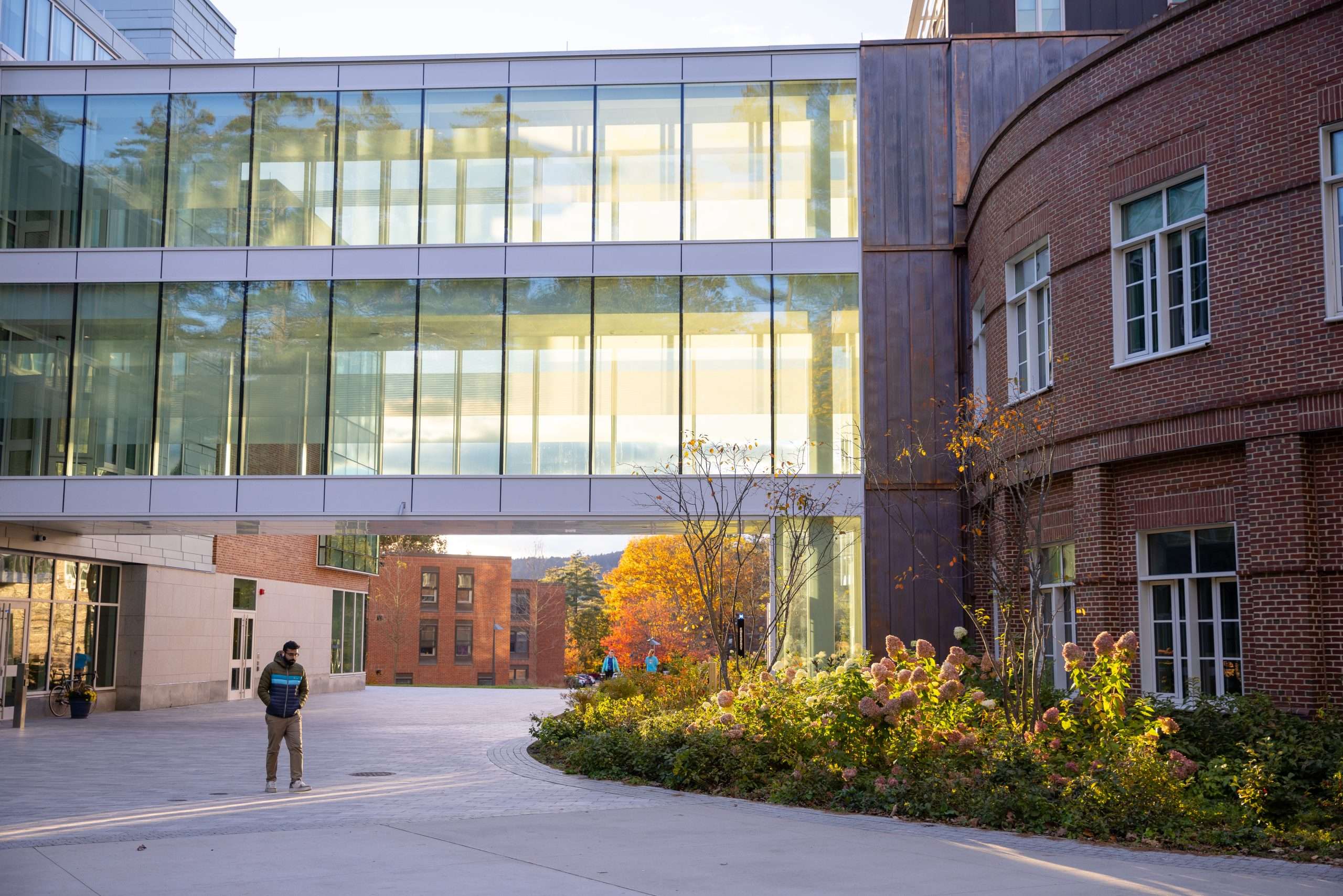 A person walks under a glass bridge connecting two buildings at Dartmouth College.