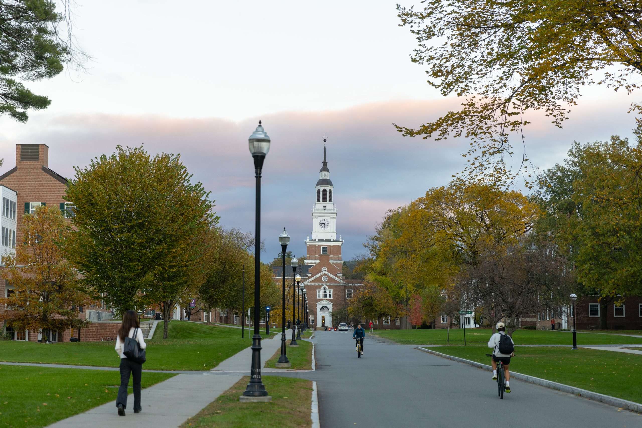 Students bike down the street at Dartmouth College, next to the campus Green.