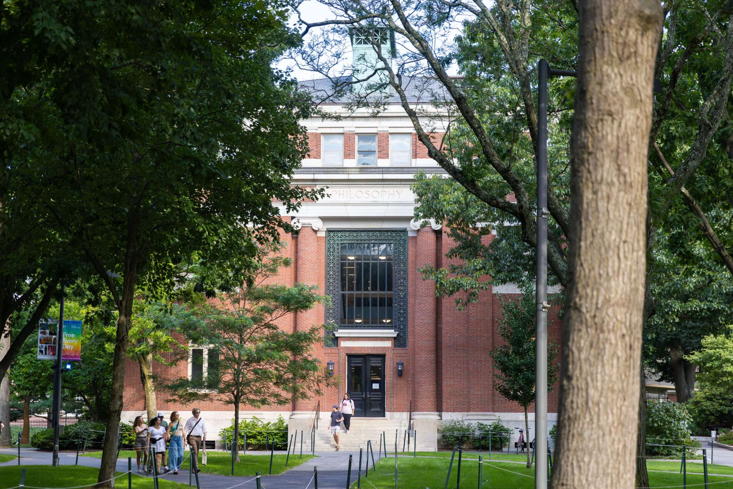 Students walk down the steps in front of the philosophy building at Harvard University.