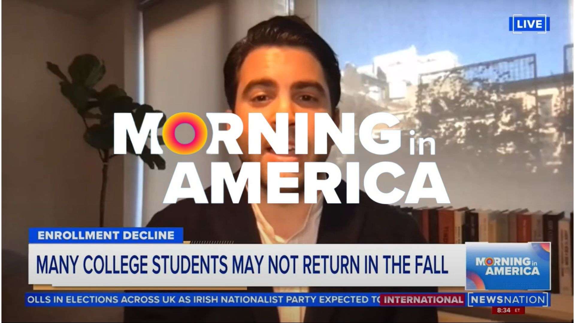 This is screenshot of Brian Taylor's appearance on Morning in America, in which he sits at an office behind the Morning in America logo and a news reel.