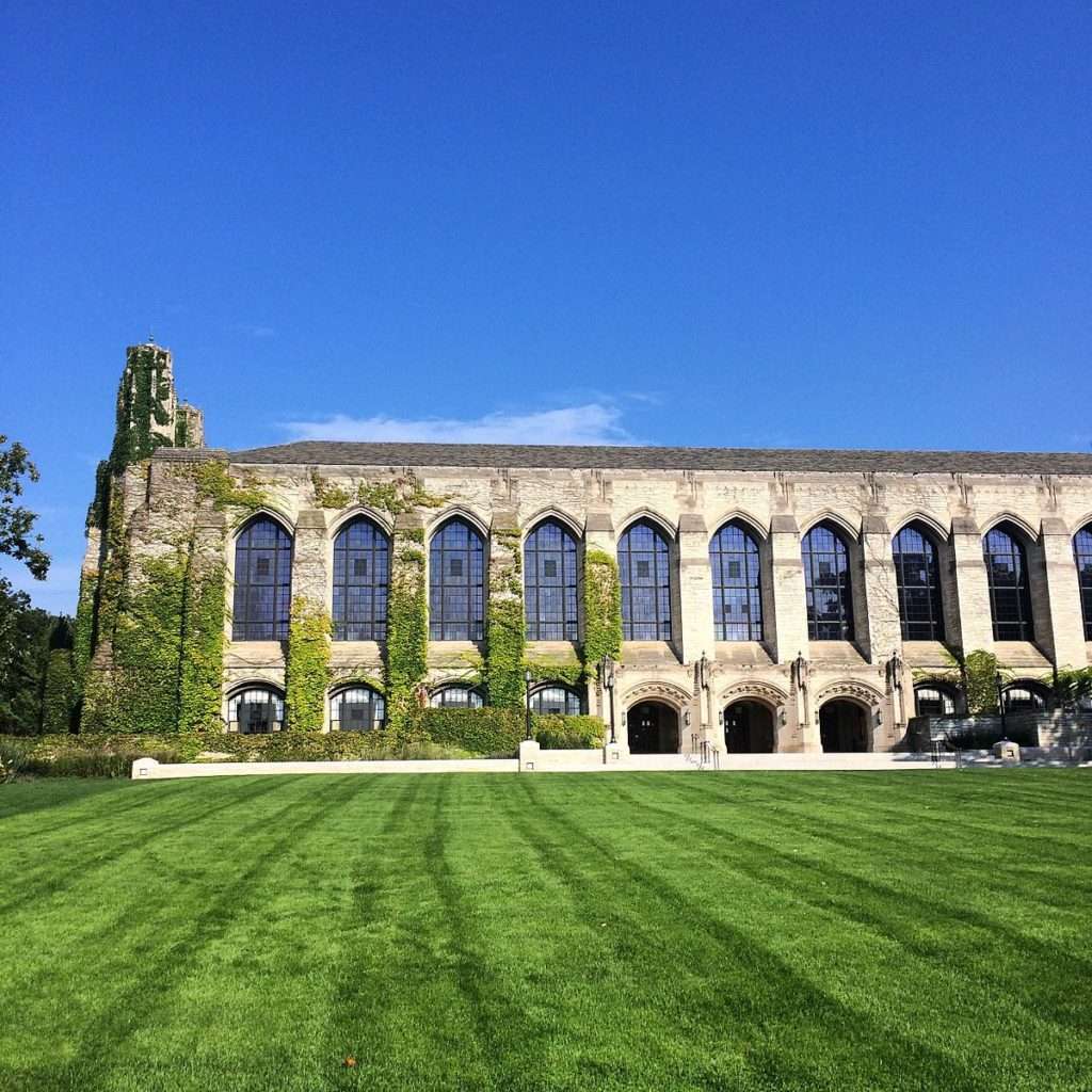 An ivy-covered building with gorgeous windows is featured beyond a well kept lawn at Northwestern University.