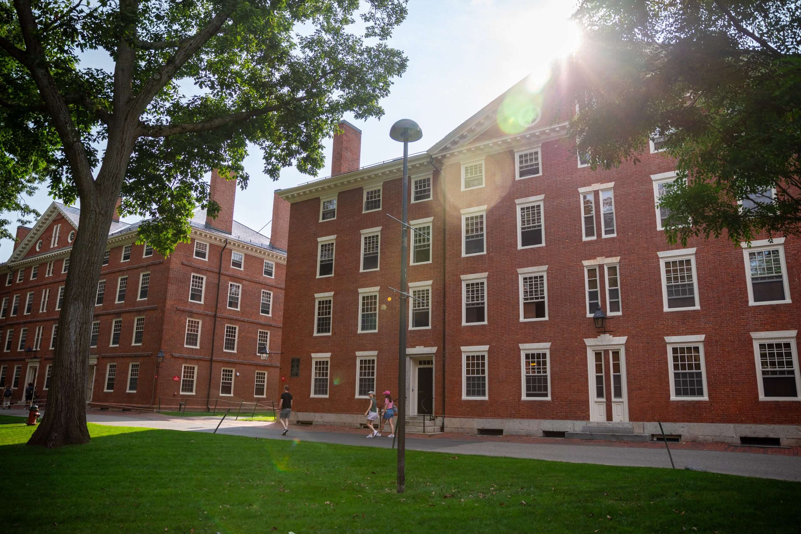 Students walk in front of red bricked buildings at Harvard University.