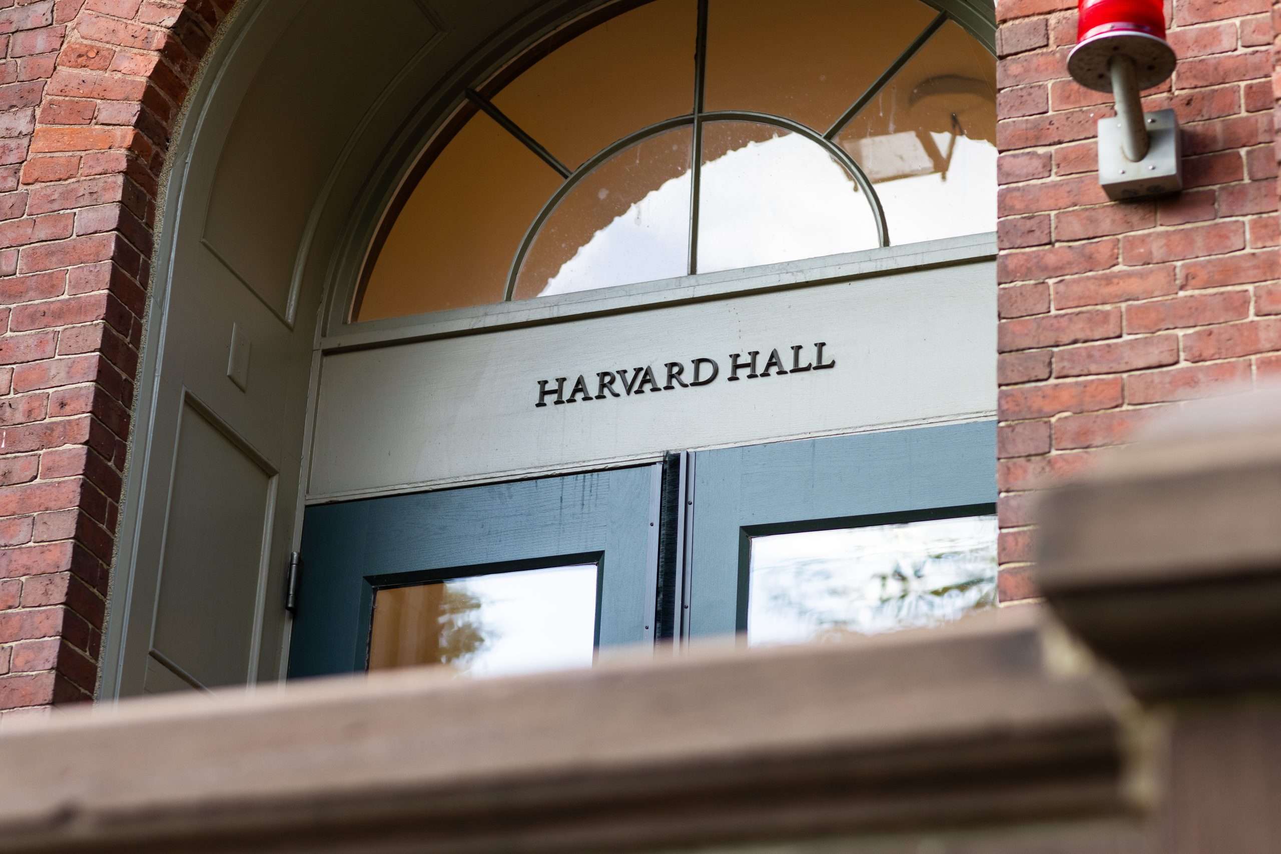 The blue glass doors that lead to Harvard Hall at Harvard University are featured.
