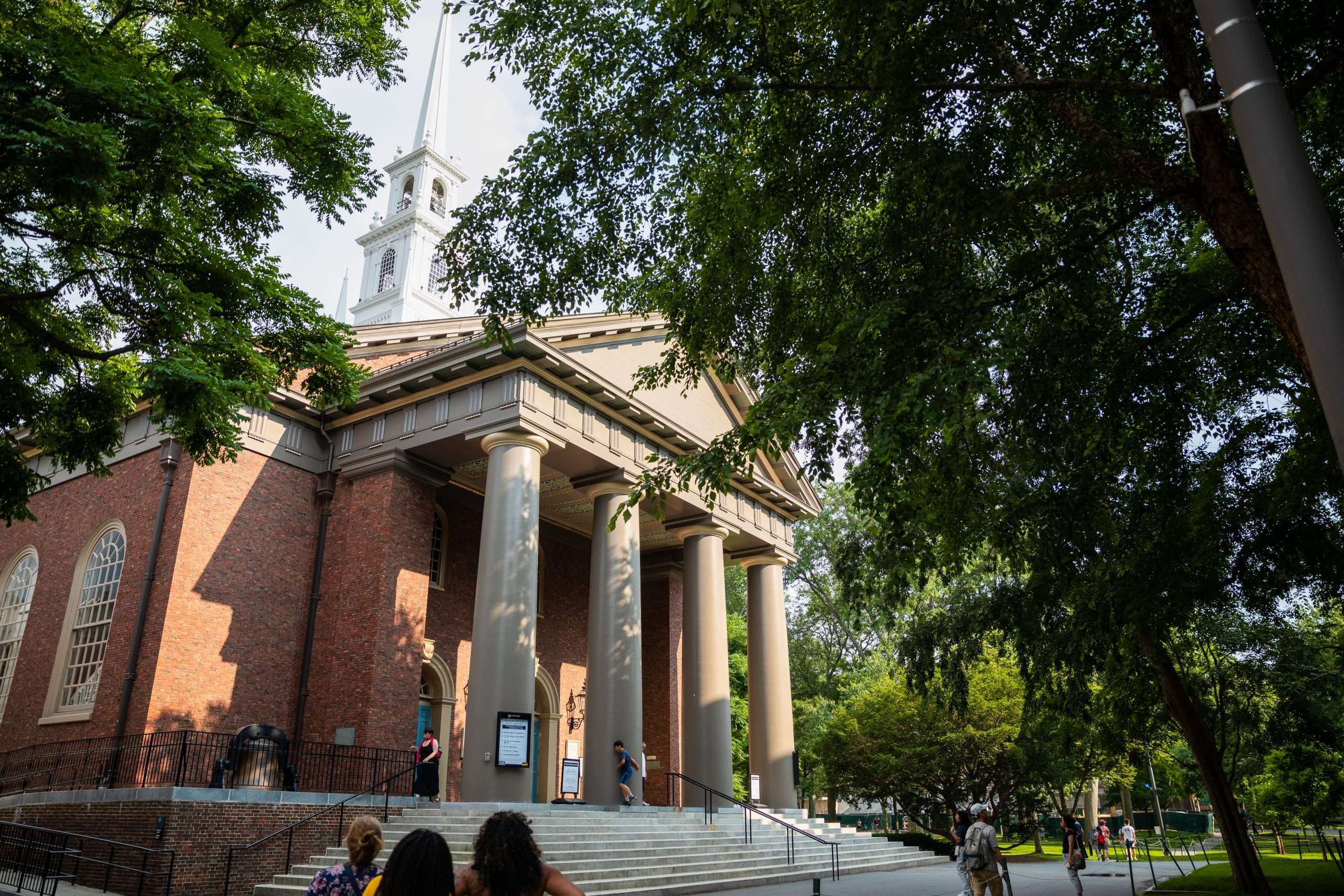 People gather outside the front steps of a columned building at Harvard University.